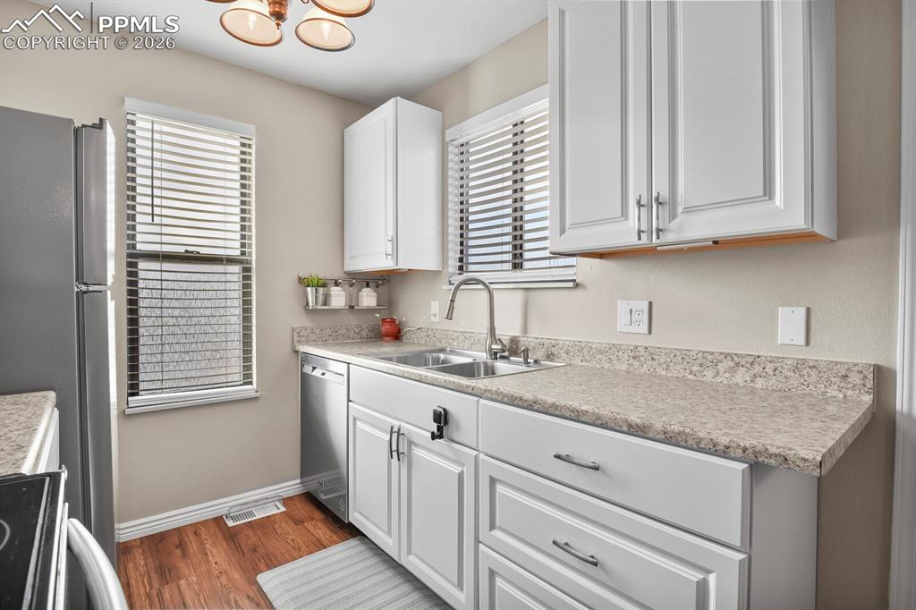 Kitchen with light countertops, white cabinetry, stainless steel appliances, and dark wood finished floors