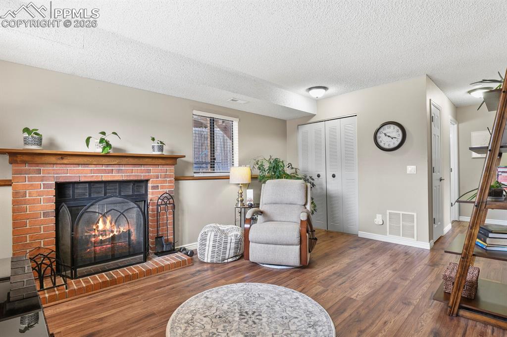 Sitting room featuring wood finished floors, a textured ceiling, and a fireplace