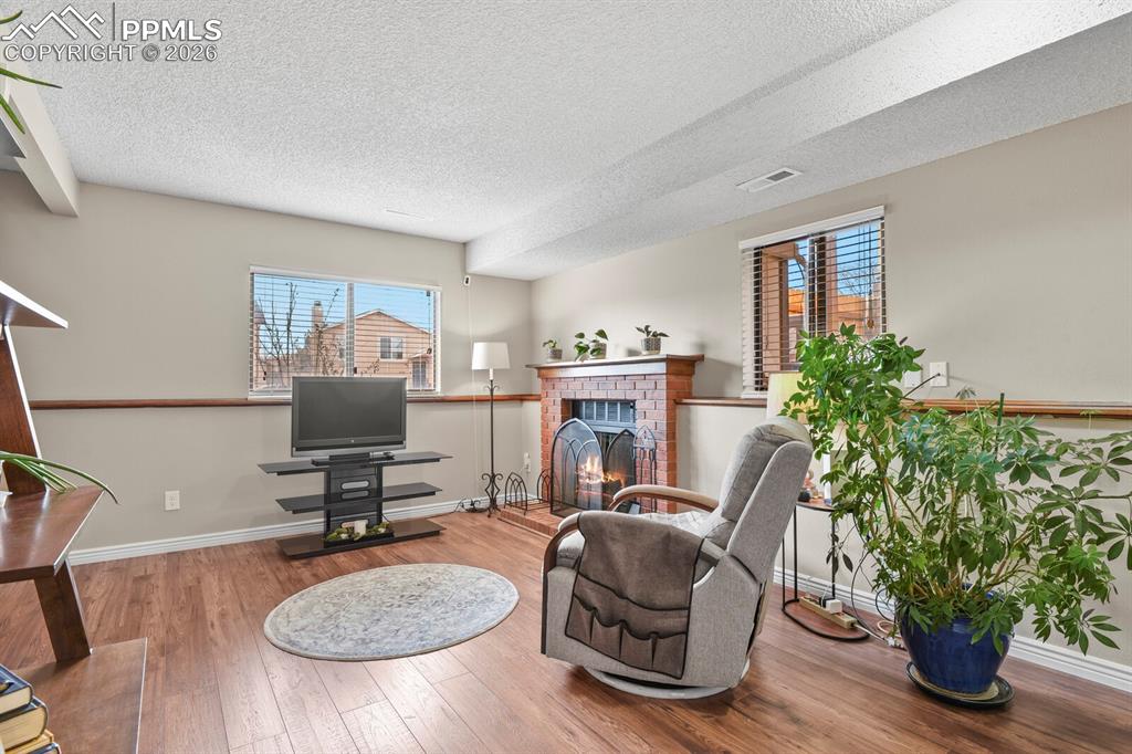 Sitting room featuring hardwood / wood-style floors, a brick fireplace, and a textured ceiling