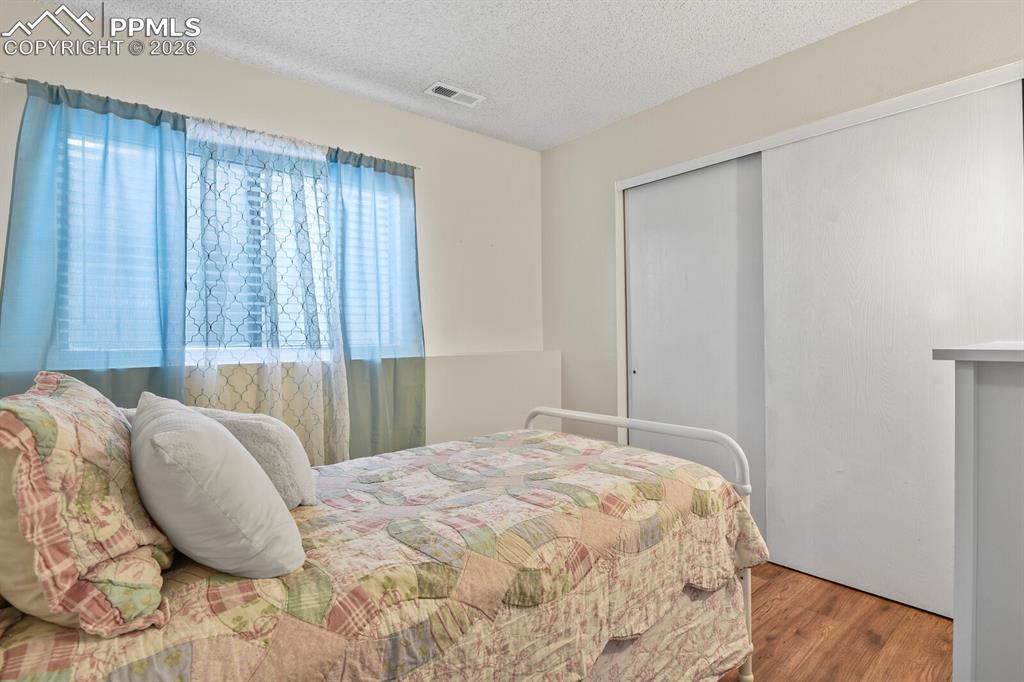 Bedroom featuring a textured ceiling, wood finished floors, and a closet