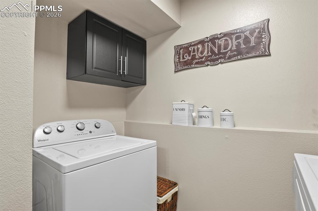 Laundry room featuring washer / clothes dryer, a textured wall, and cabinet space