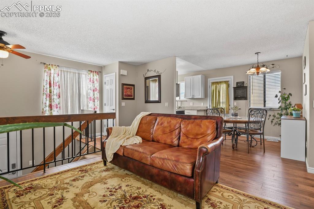 Living area featuring wood finished floors, a textured ceiling, a ceiling fan, plenty of natural light, and suspended lighting