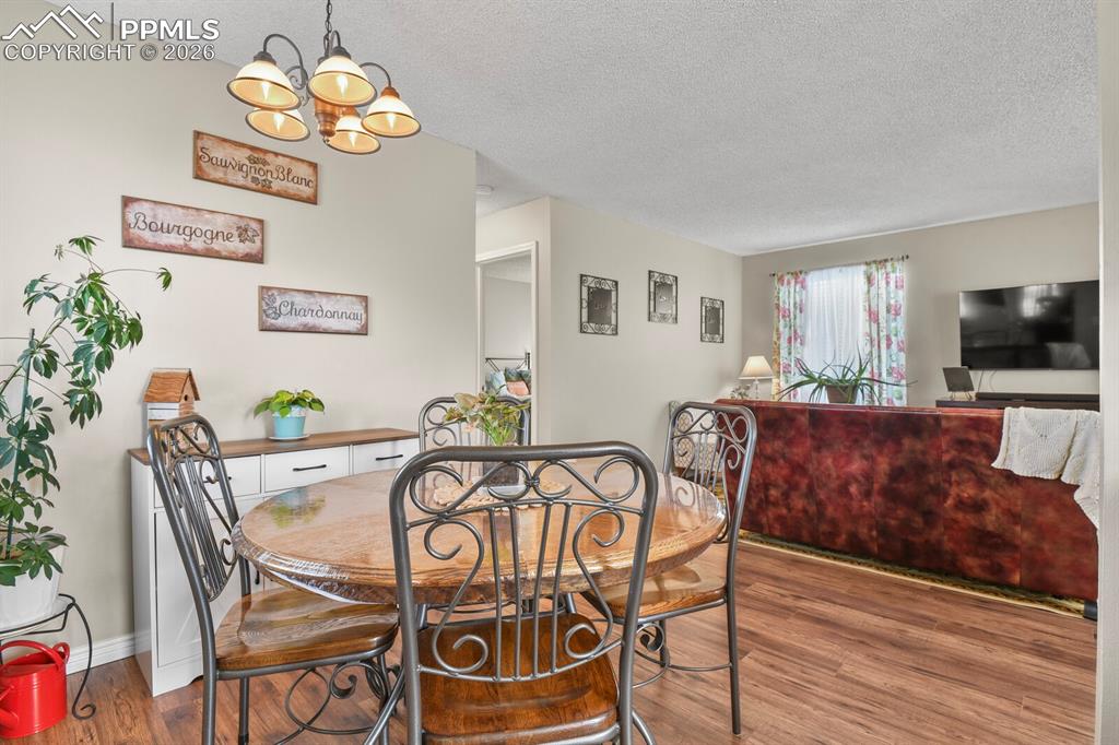 Dining area with hanging lights, a textured ceiling, and dark wood-type flooring