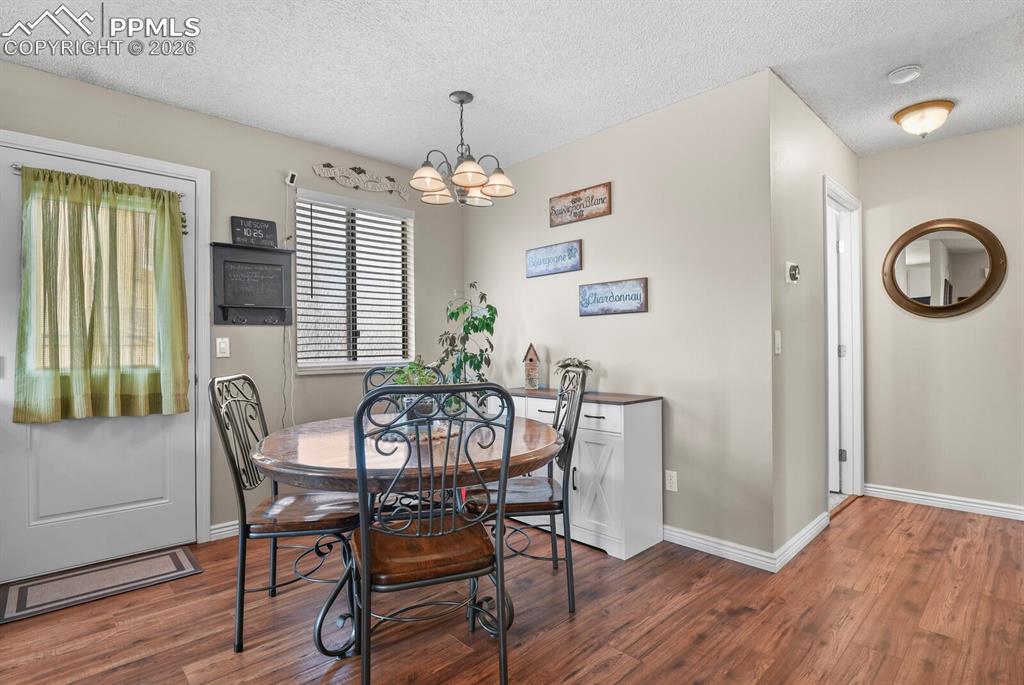 Dining space featuring hanging lights, dark wood-style floors, and a textured ceiling