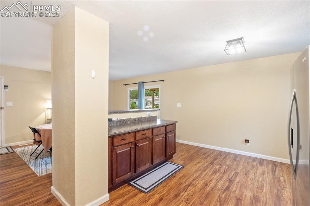 Kitchen featuring light wood-style flooring, dark countertops, and freestanding refrigerator