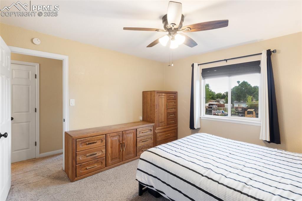 Bedroom with light colored carpet and a ceiling fan
