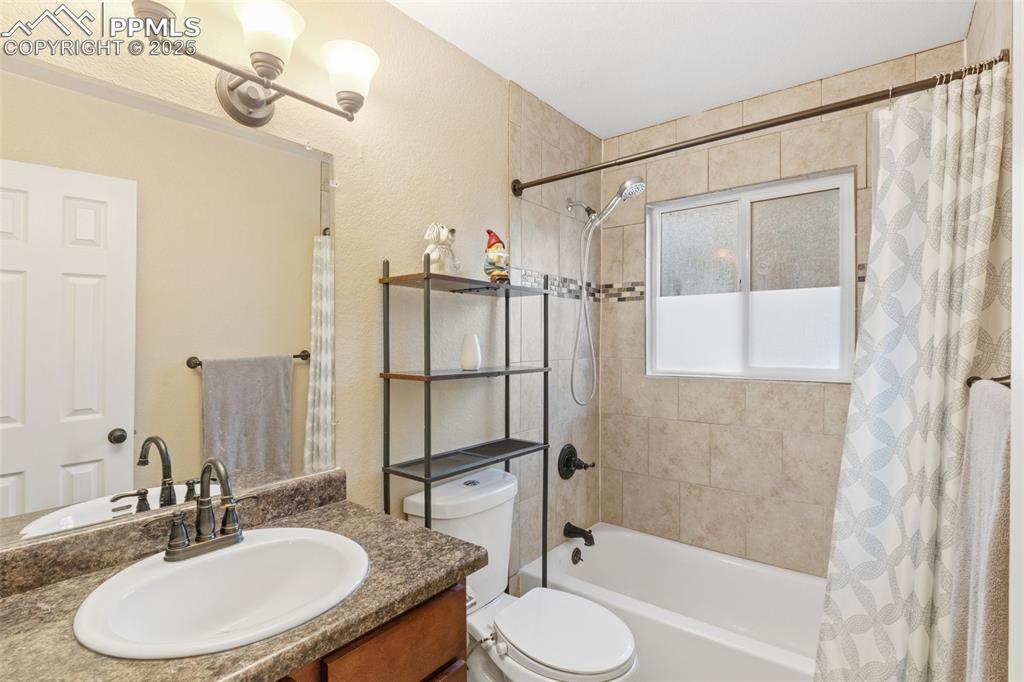 Bathroom featuring shower / bath combo, vanity, and a textured wall