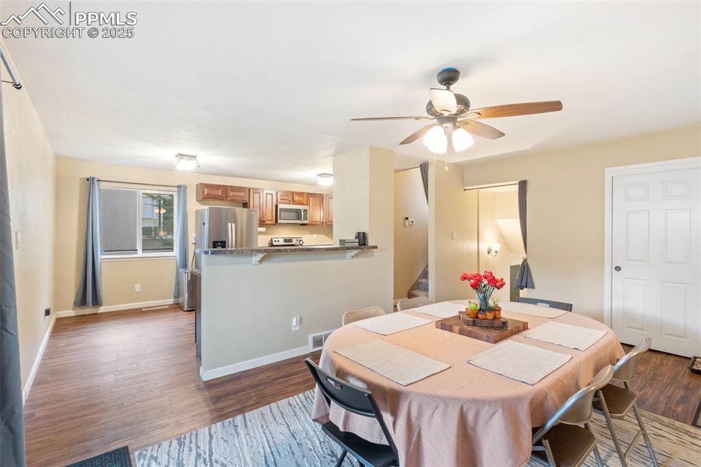 Dining room with stairway, dark wood-style flooring, and a ceiling fan
