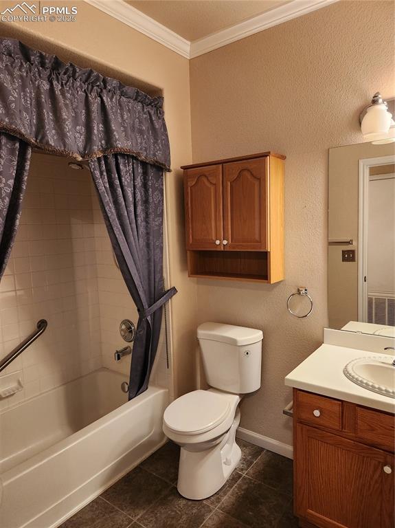 Full bathroom featuring crown molding, a textured wall, shower / bath combo, vanity, and dark tile patterned flooring