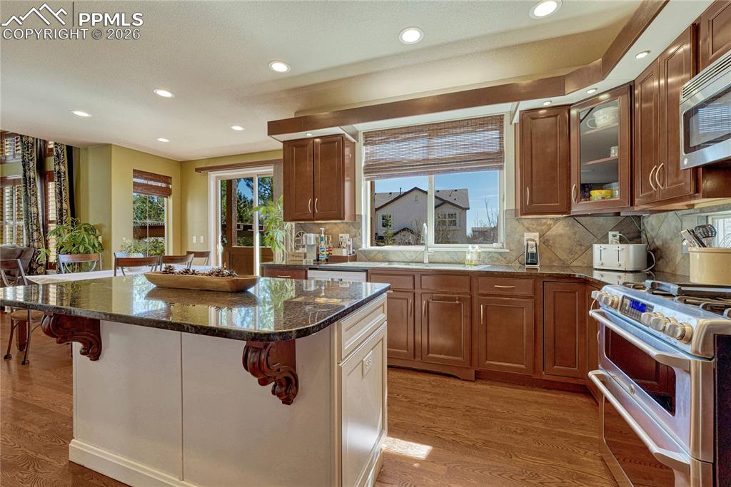 Kitchen sink with window views, custom cabinetry, and full height backsplash