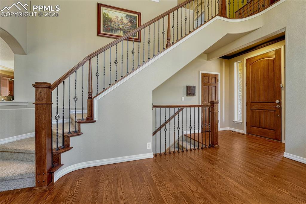 Entry staircase with wrought-iron balusters and hardwood floors