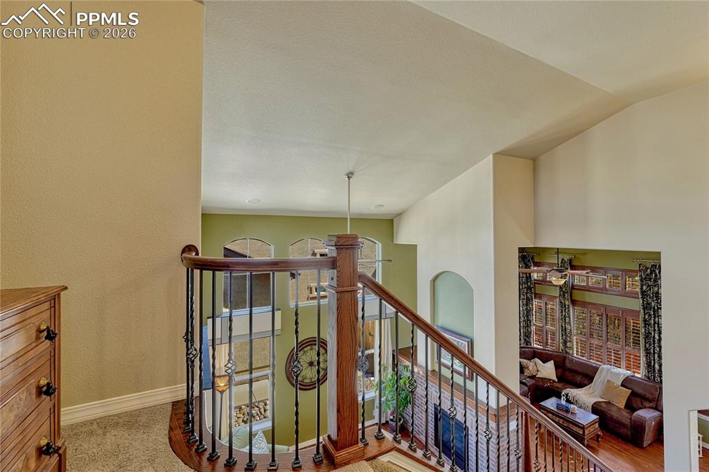 Upper-level landing overlooking vaulted living space and fireplace