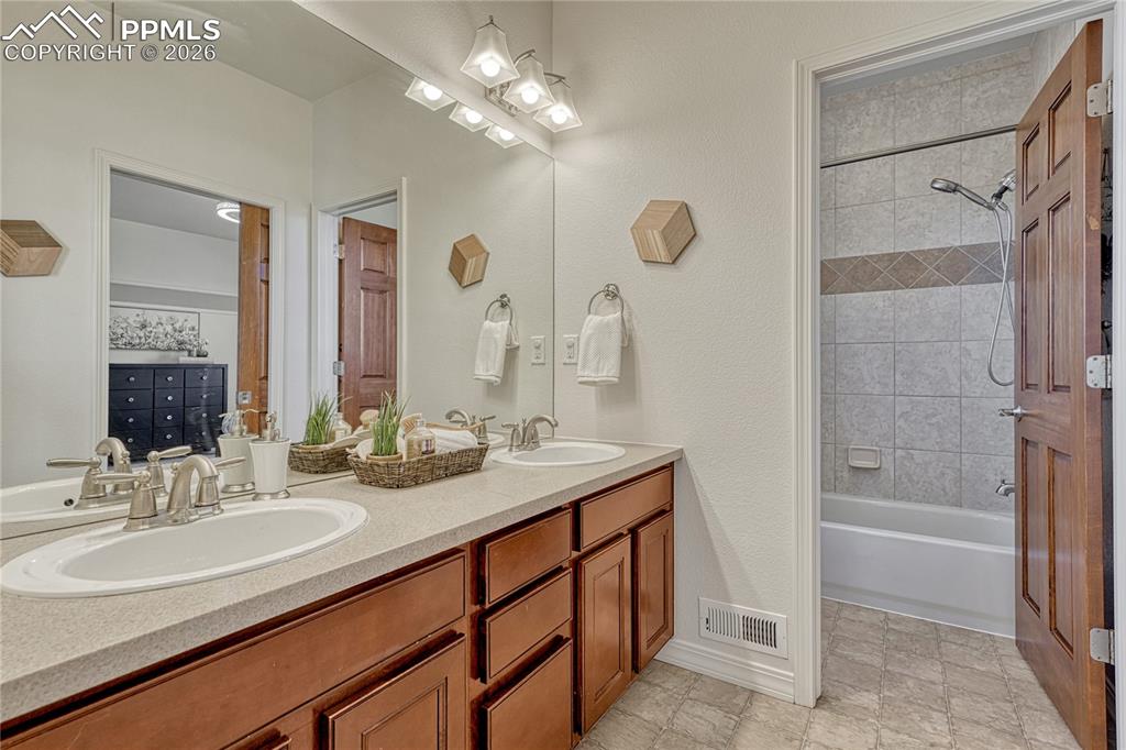 Fully shared bathroom with dual vanities and separate shower area