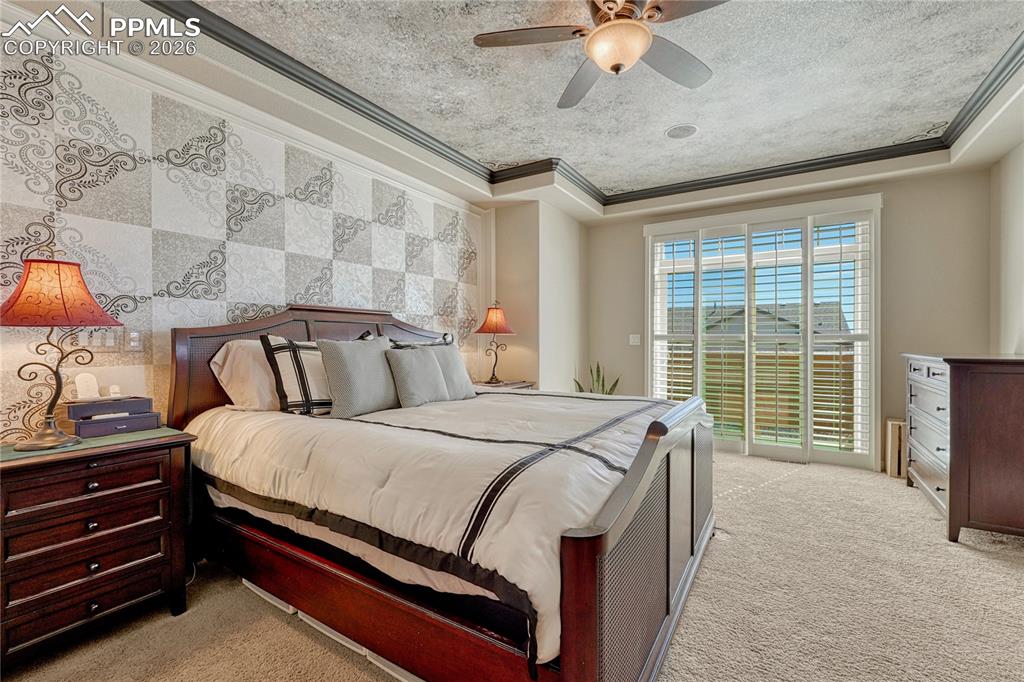 Primary bedroom with tray ceiling, crown moulding and balcony access