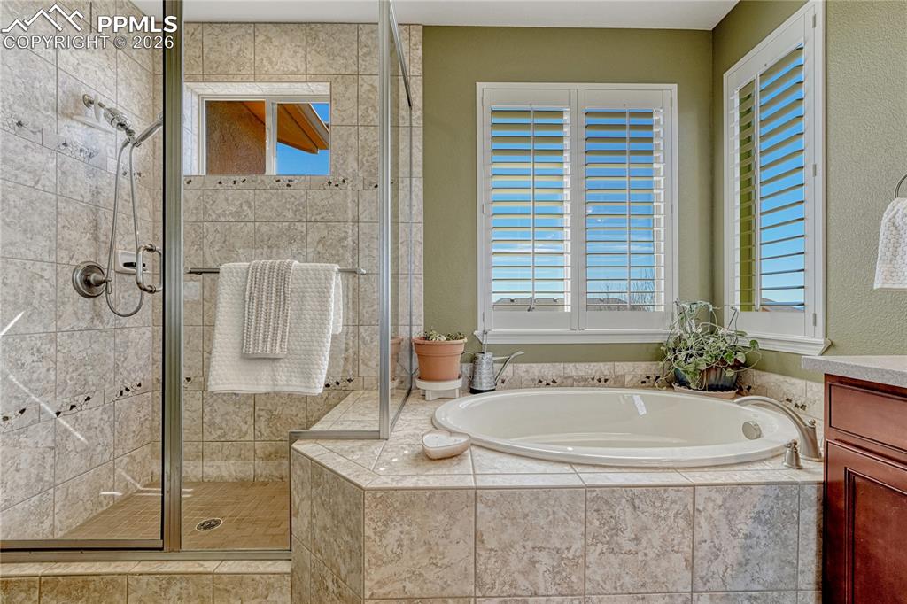 Large walk-in shower and soaking tub with plantain shutters for added privacy