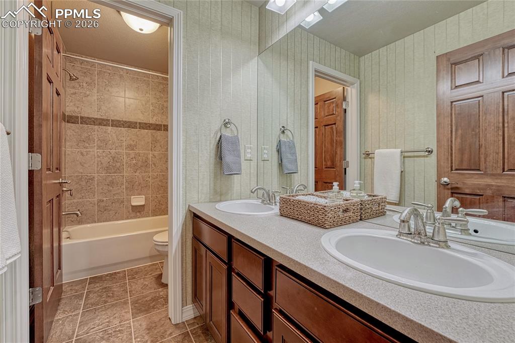 Full basement bathroom with dual vanities near guest bedrooms