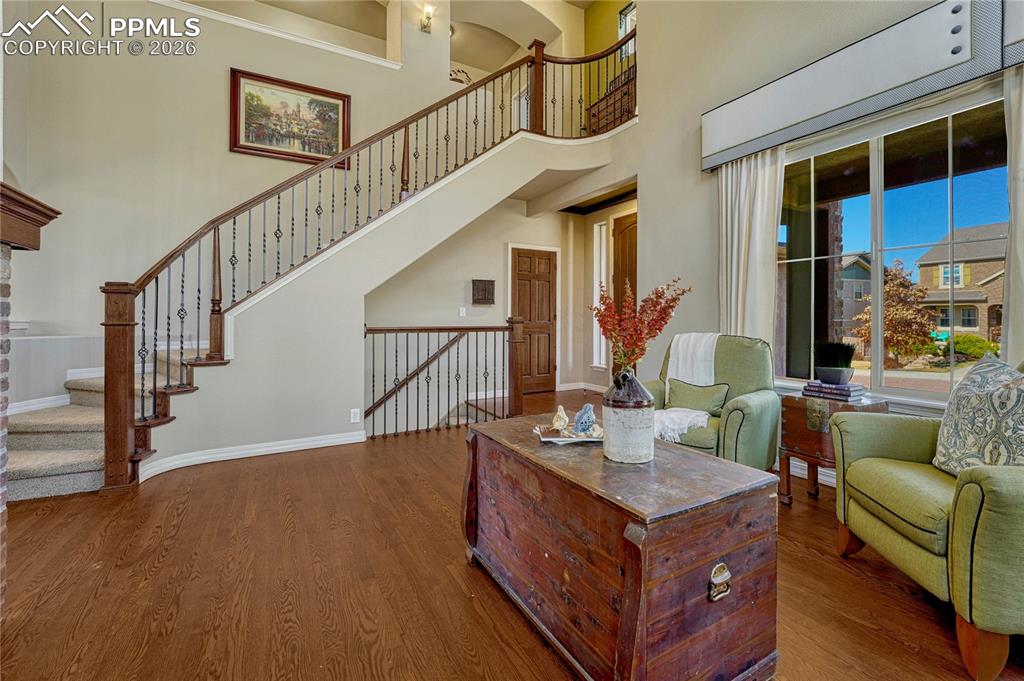 Open entry and living room with wood and decorative wrought iron staircase