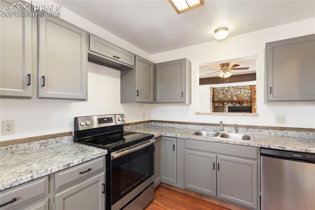 The kitchen features gray cabinets, stainless steel appliances, and light countertops!