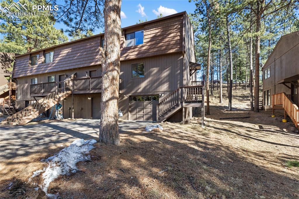 The front of the home with a one car garage, driveway, and tall mature trees!