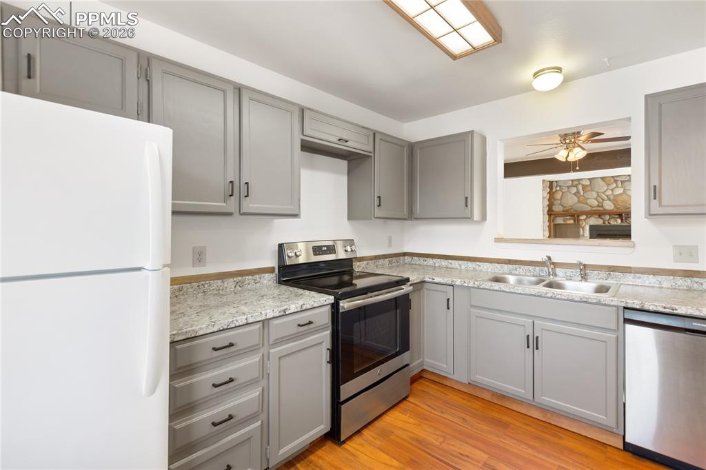 The kitchen features gray cabinets, stainless steel appliances, and light countertops!