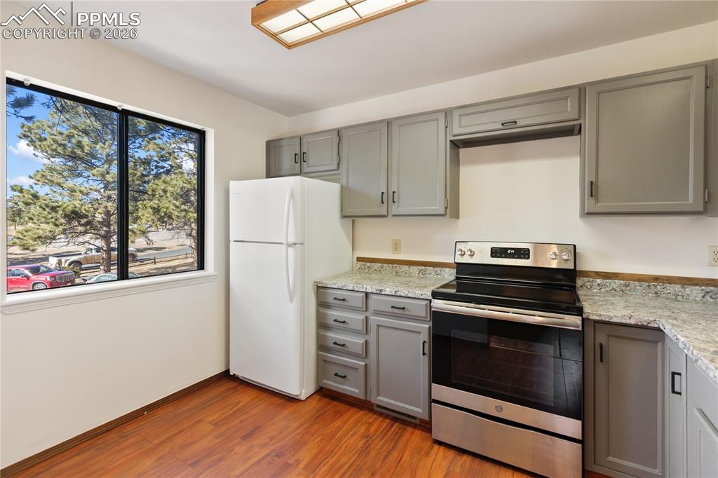 The kitchen features gray cabinets, stainless steel appliances, and light countertops!