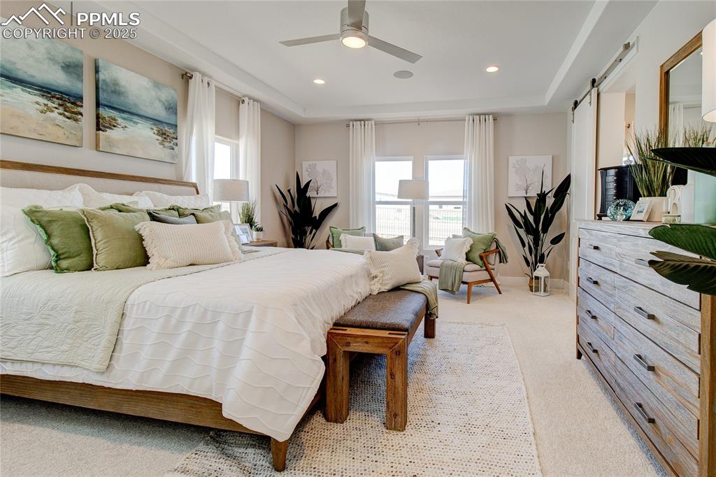 Bedroom with light carpet, multiple windows, a barn door, a ceiling fan, and recessed lighting