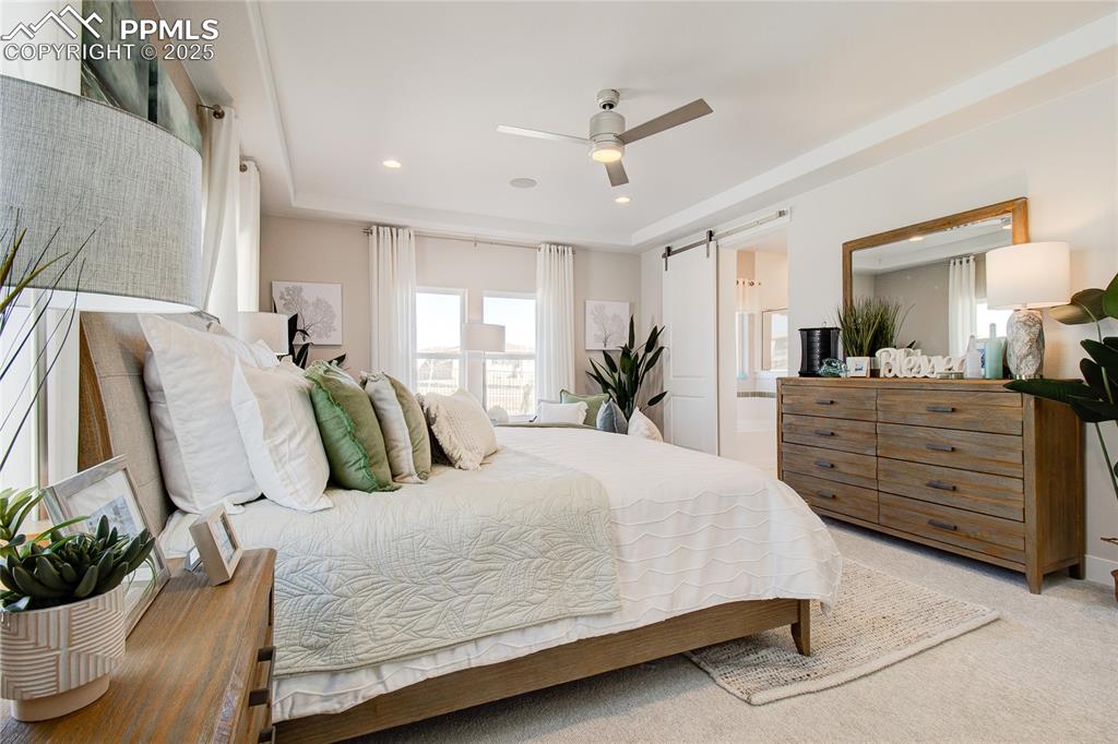 Bedroom with a barn door, light carpet, connected bathroom, recessed lighting, and ceiling fan