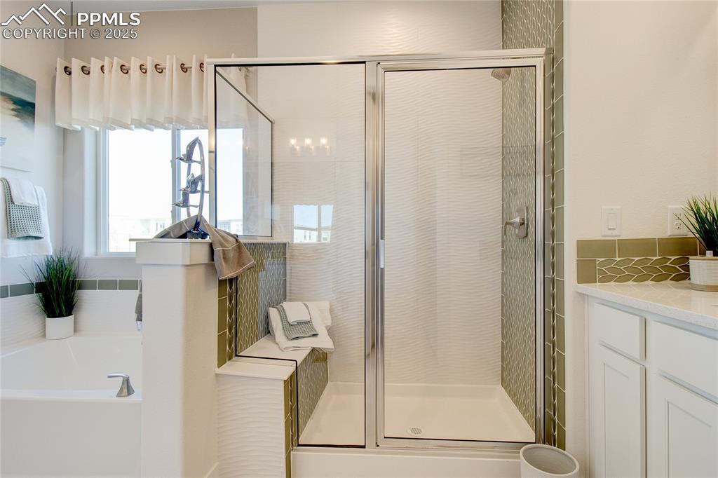 Full bathroom featuring a stall shower, a bath, and vanity