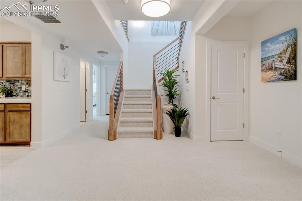 Carpeted foyer featuring stairway and baseboards