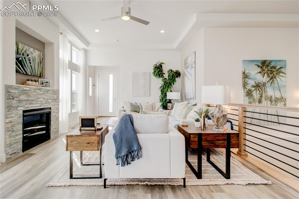 Living area with a ceiling fan, wood finished floors, and a fireplace