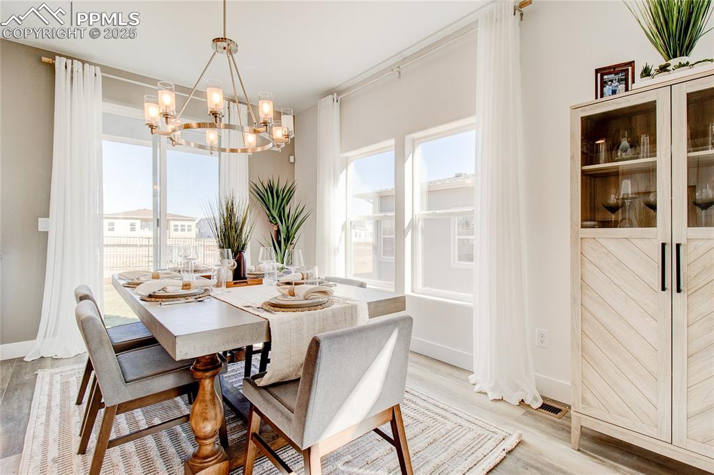 Dining room with healthy amount of natural light, a chandelier, and light wood finished floors