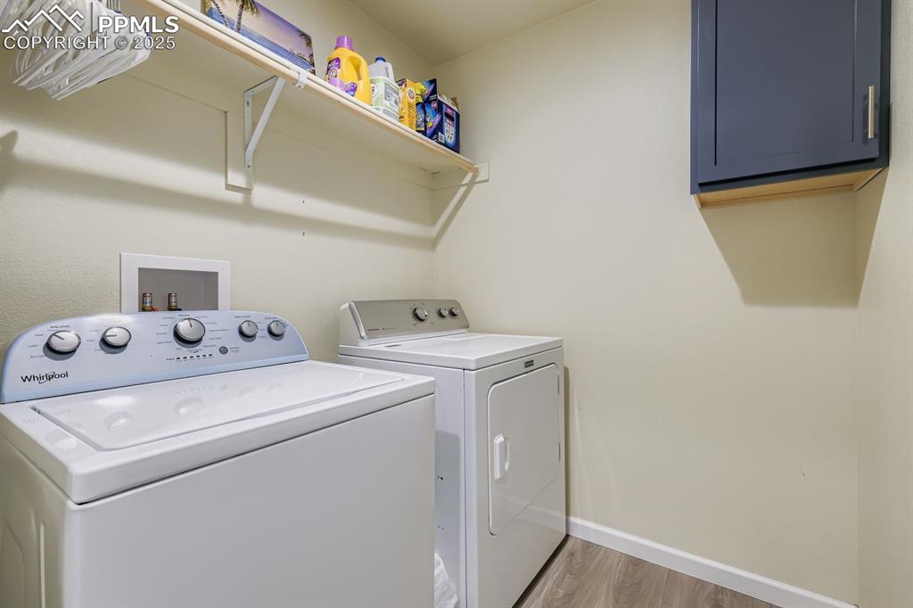 Laundry room with light wood-type flooring, separate washer and dryer, and cabinet space