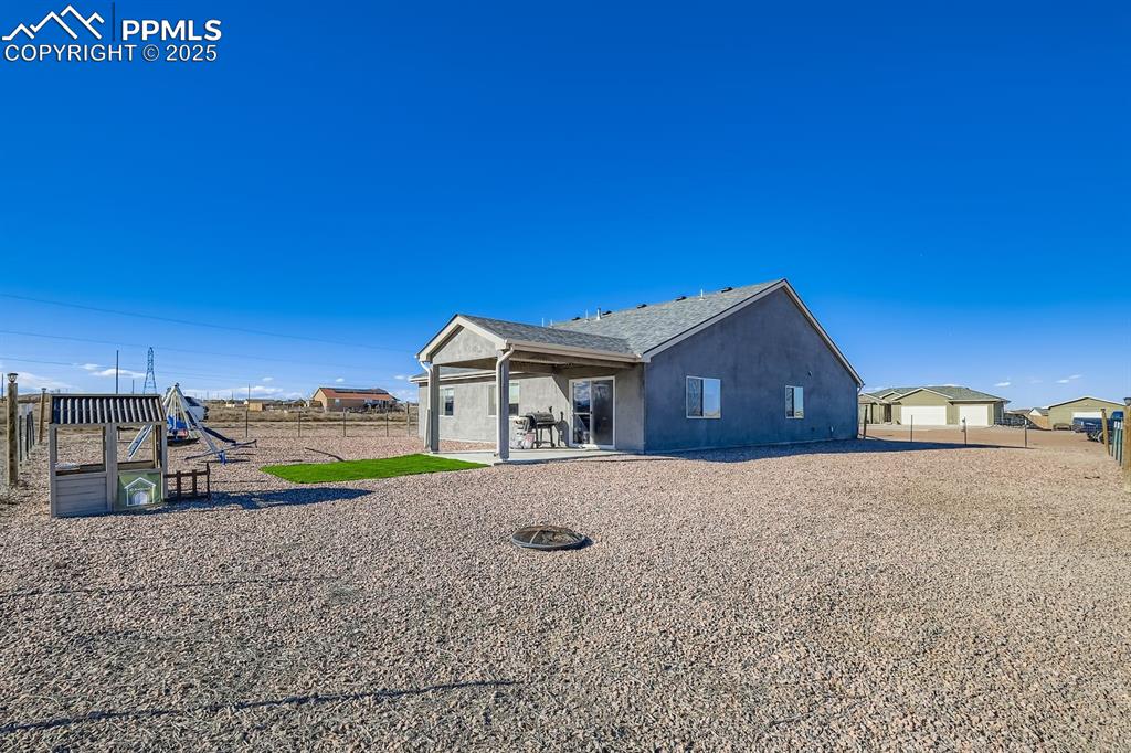 View of side of property with a patio area, a fenced backyard, a playground, and stucco siding