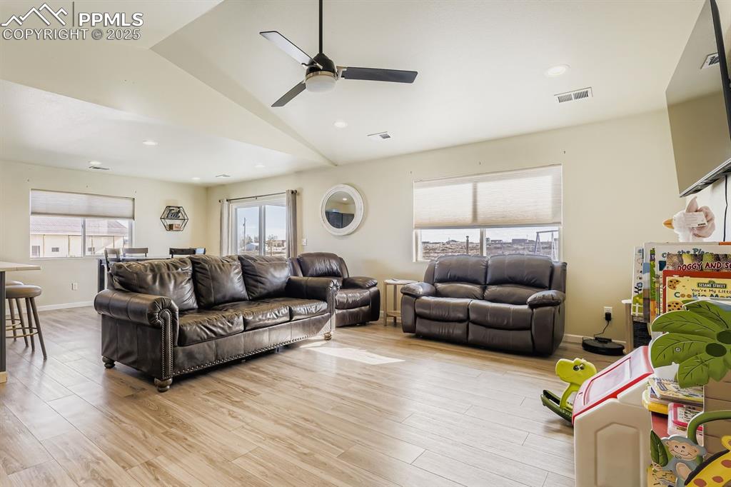 Living room featuring lofted ceiling, light wood finished floors, ceiling fan, and recessed lighting