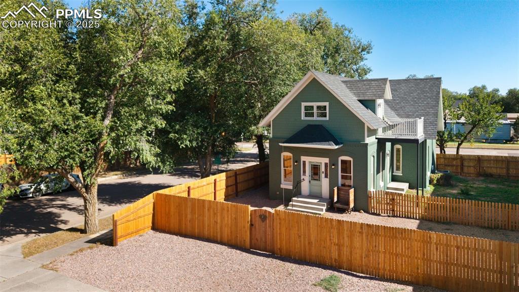 View of front of home featuring a fenced front yard, a shingled roof, and a gate