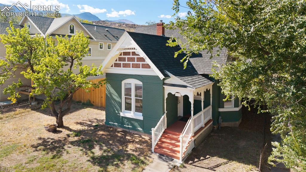View of front of home with a shingled roof, a mountain view, a porch, and a chimney