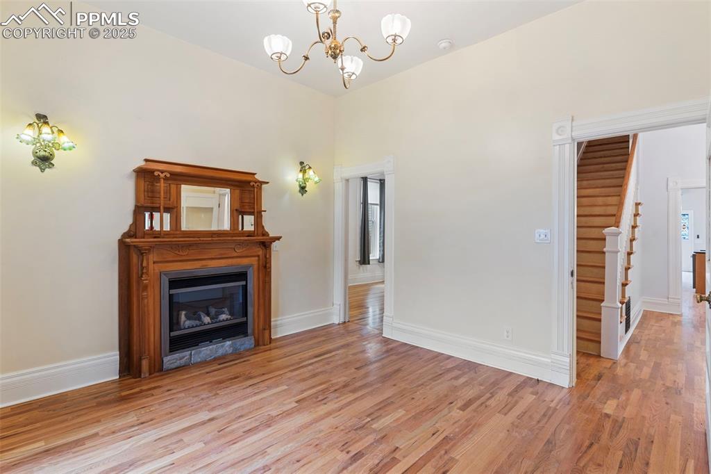 Unfurnished living room with light wood finished floors, a glass covered fireplace, and a chandelier