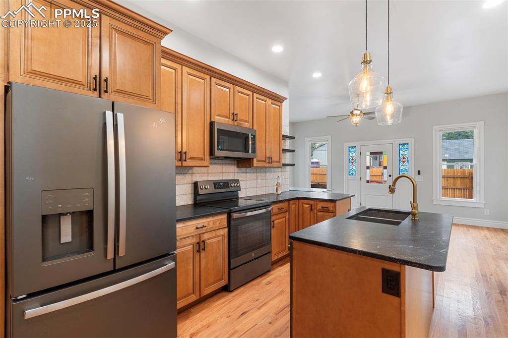 Kitchen featuring appliances with stainless steel finishes, dark countertops, tasteful backsplash, light wood-type flooring, and recessed lighting