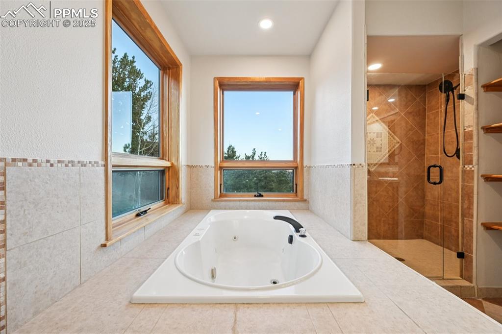 Primary bathroom highlighting the jetted tub with private mountain views out of the windows