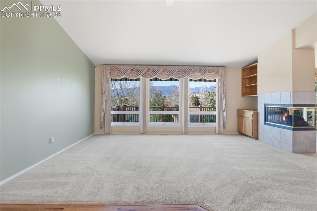 Unfurnished living room featuring light colored carpet, a tiled fireplace, and a mountain view