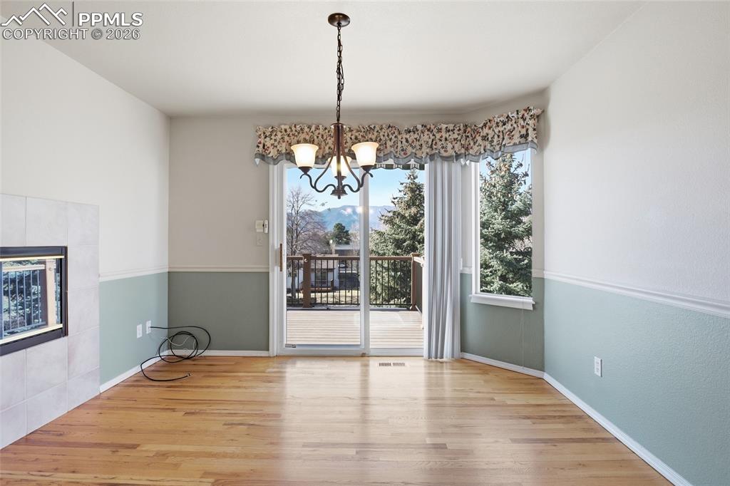 Unfurnished dining area featuring light wood finished floors, a tile fireplace, and suspended lighting
