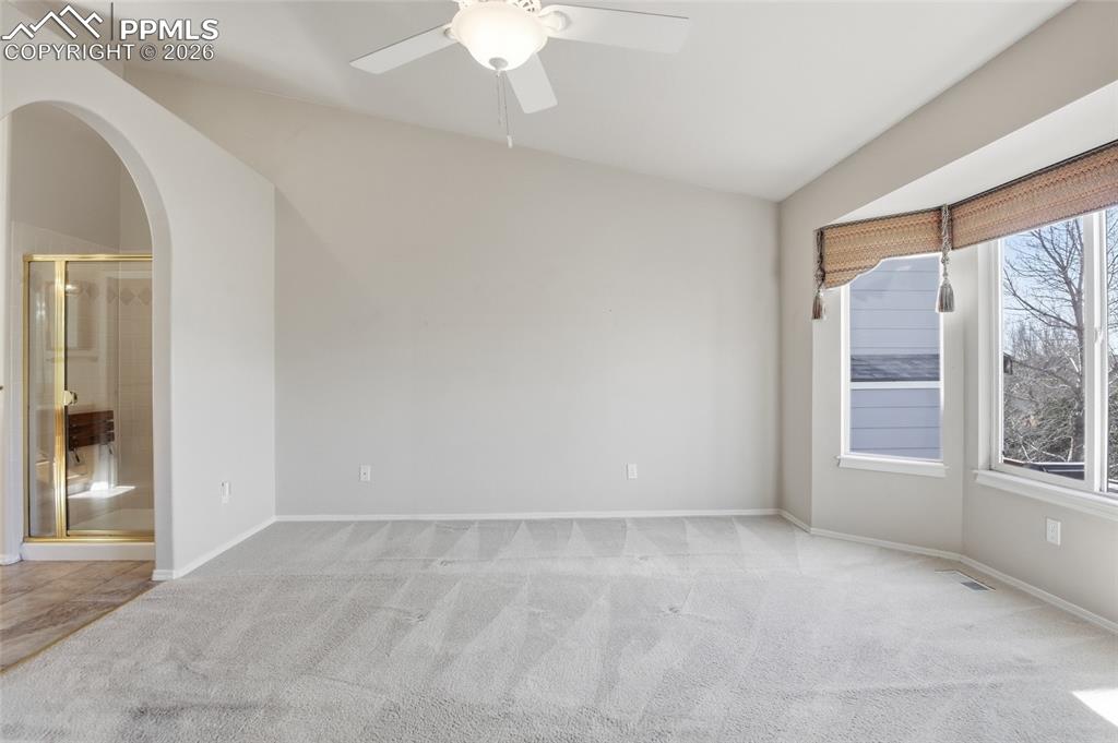 Spare room featuring light carpet, ceiling fan, and arched walkways