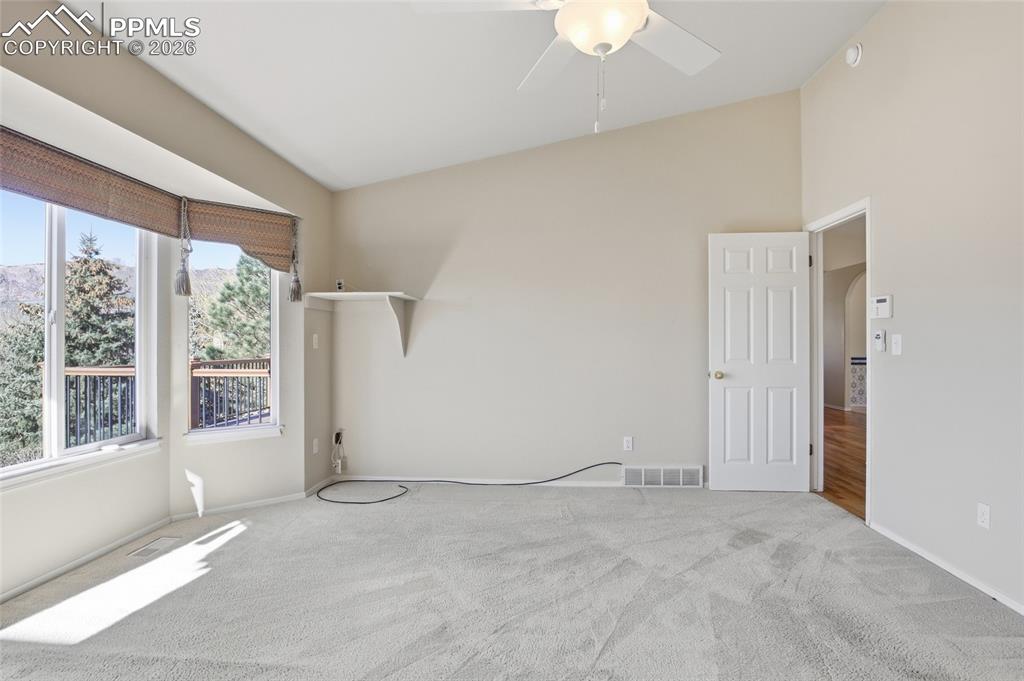 Spare room with carpet floors, ceiling fan, lofted ceiling, and arched walkways