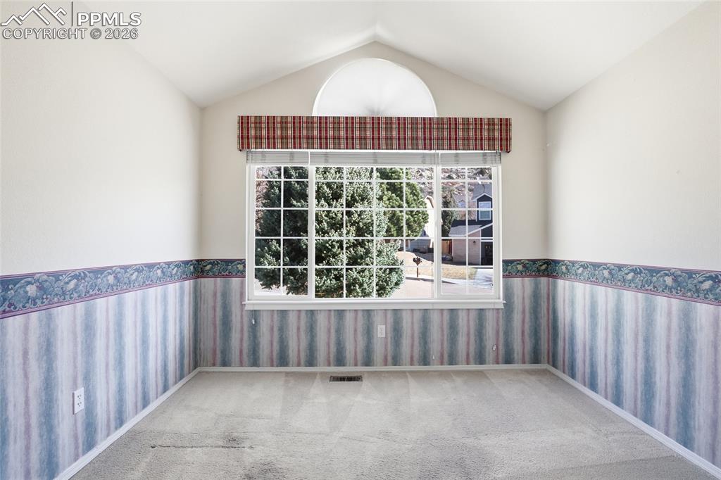 Unfurnished room featuring wallpapered walls, wainscoting, plenty of natural light, and light colored carpet