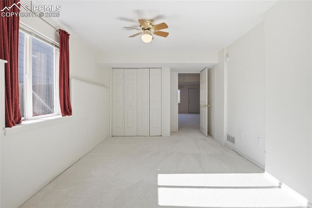 Unfurnished bedroom featuring light carpet, a ceiling fan, and a closet