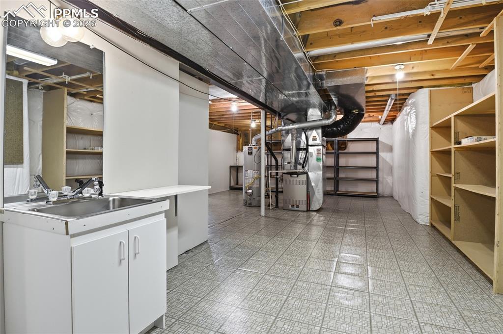 Unfinished below grade area with light floors, heating unit, and water heater