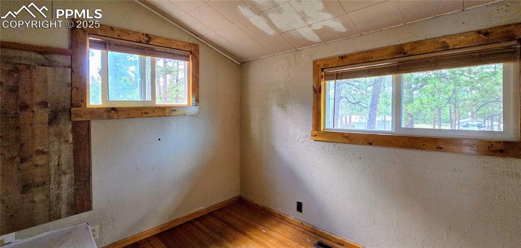 Spare room featuring a textured wall, hardwood / wood-style flooring, and lofted ceiling