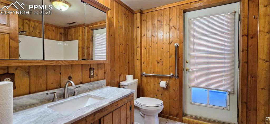 Bathroom with wooden walls, healthy amount of natural light, vanity, and tile patterned flooring
