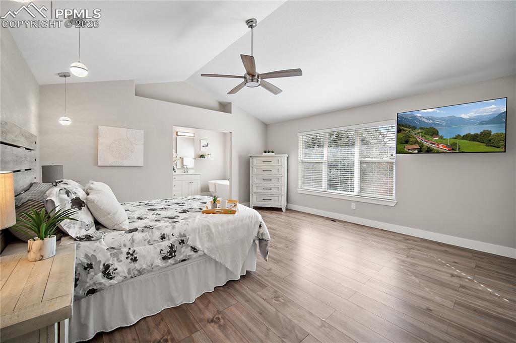Primary bedroom with vaulted ceilings, laminate flooring, new paint and lighting. 