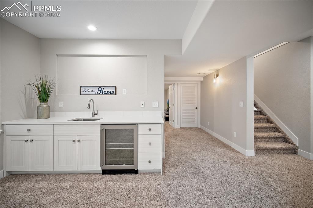 Basement wet bar with sink and beverage fridge. 